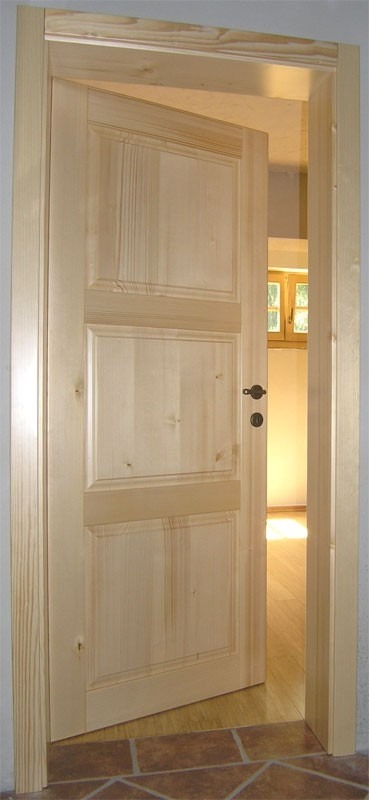 Lesena notranja vrata z modernim okvirjem v svetlem dnevnem prostoru.